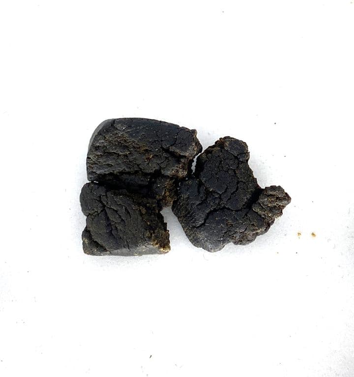 Dark black temple ball hash rolled into a dense sphere showing rich resinous texture and traditional handcrafted form